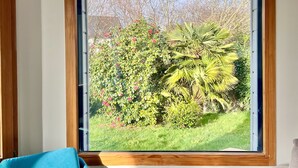 Una habitación con un gran ventanal que da a un jardín con diversas plantas y árboles.