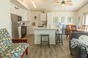 A modern kitchen with white cabinets, a central island with stools, and a dining area with wooden chairs. - Family fun! Perfect for families to make memories (Freeport)