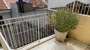 A balcony with a white metal railing, a potted plant, and a tiled floor. - Sobrado Tranquilo, rua Silenciosa (Jardim São Paulo São Paulo)