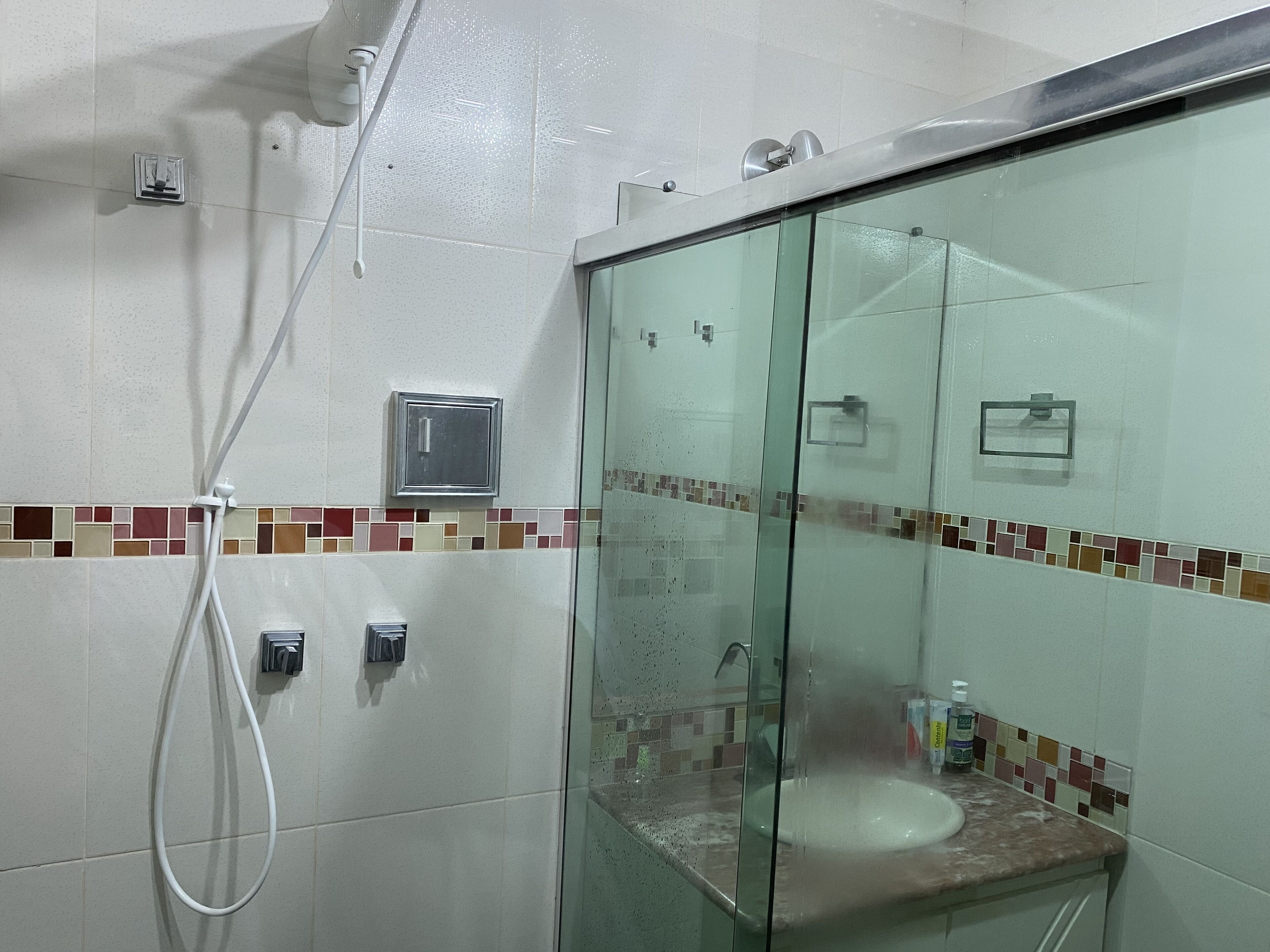 A bathroom with a glass shower enclosure, a sink, and a tiled backsplash.