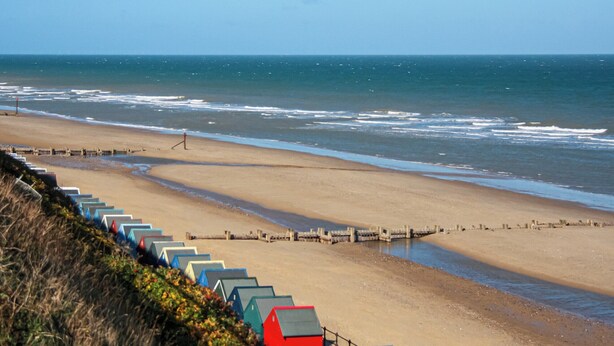 A beach with a row of colorful beach huts along the shore. - 2 bedroom accommodation in Mundesley (Mundesley)