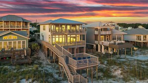 Une propriété située en bord de mer, comprenant plusieurs bâtiments, notamment une maison principale dotée d’un balcon et une autre construction séparée avec une terrasse.