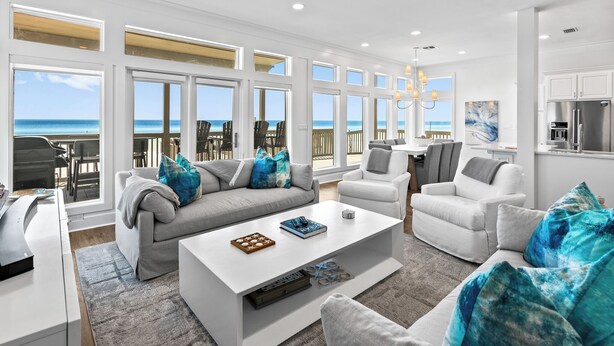 Un salon spacieux avec un canapé blanc, une table basse et une vue sur l’océan.