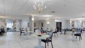 A spacious hotel lobby with multiple round tables and chairs, elegant chandeliers, and framed artwork on the walls. - The View Hotel, Trademark Collection by Wyndham (Orlando)