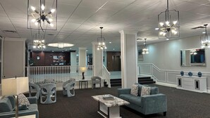A spacious lobby with modern furniture, a staircase, and multiple hanging light fixtures. - The View Hotel, Trademark Collection by Wyndham (Orlando)