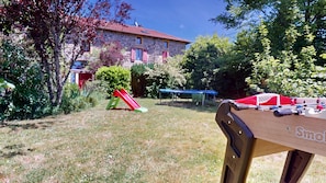Ein Steinhaus mit rotem Dach, einer Rutsche und einem Tisch mit Spielzeug.