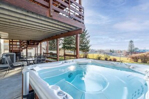 Un jacuzzi debajo de una terraza de madera con vistas a un campo y árboles.