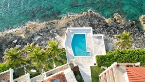 An aerial view of a resort with a swimming pool surrounded by rocky terrain and palm trees. - Delaporte Point Near waterpark Private Beach! (Nassau)