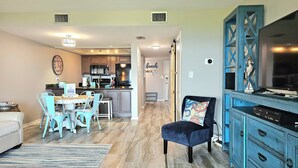 A spacious living room with a dining area, a kitchen, and a TV area. - Pensacola Beach Waterfront Condo with Relaxing View. Family Friendly! (Pensacola Beach)