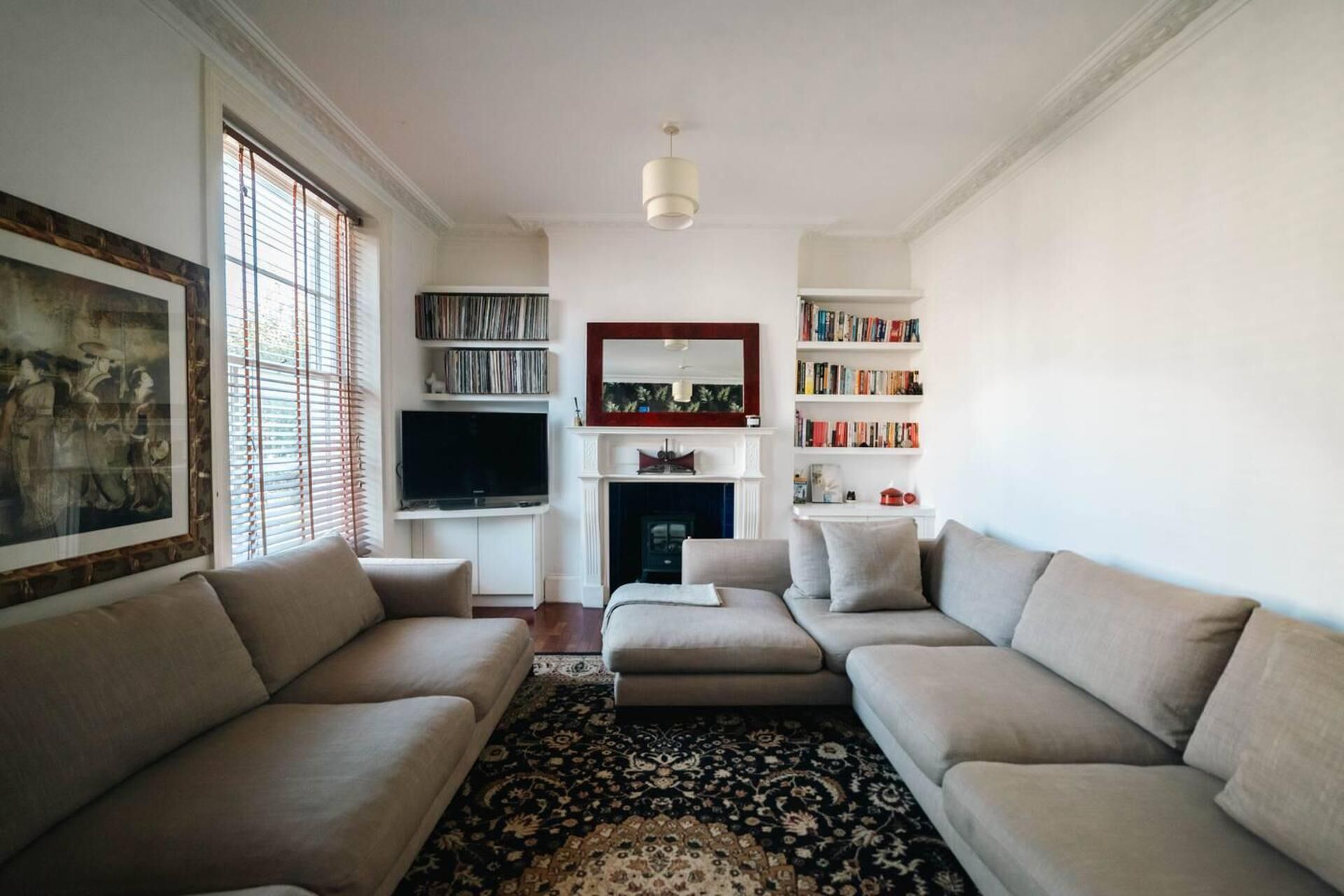 Una sala de estar con un sofá, televisor, estanterías y chimenea.