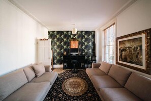 A living room with two sofas, a black patterned rug, a desk with a computer, and a painting on the wall. - Stylish 2 Bedroom Flat in Camden Town (London)