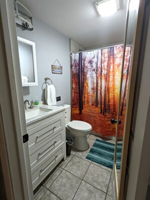 A bathroom with a sink, toilet, and a window with a forest view. - 2b1b fenced backyard with deck, outdoor space near hospitals (Springfield)