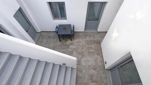 Un edificio moderno con una escalera, una pequeña zona de estar al aire libre y una puerta.