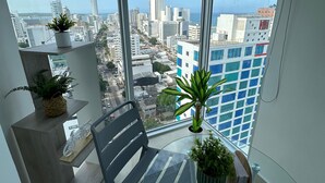 A balcony with a view of a cityscape, a chair, and potted plants. - Apartamento loft de 1hab vista al mar (Cartagena)