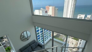 A modern apartment with a large balcony, a staircase, and a view of the city and ocean. - Apartamento loft de 1hab vista al mar (Cartagena)