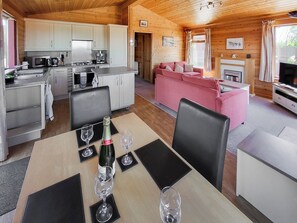 A wooden cabin interior with a kitchen, dining area, and living room.