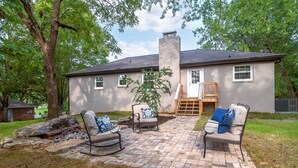 Une maison avec une terrasse en briques, deux fauteuils à bascule et une terrasse en bois.
