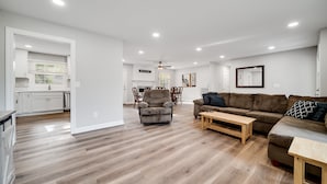Un vaste espace de vie doté d’un plancher en bois, d’un canapé, d’un fauteuil et d’une table à manger.
