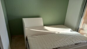 A small, single-bed room with a white bed and a green wall. - Beau Studio Mar Vivo (La Seyne-sur-Mer)