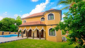 A two-story house with a swimming pool, a well-maintained lawn, and a palm tree. - Le'Lavion's Pool Villa w/Airport svc. & Private Chef/Ocho Rios Tower Isle (Ocho, Rios, Jamaca)