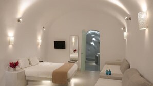 Un dormitorio moderno y minimalista con una cama grande, un sofá y una pequeña mesa.