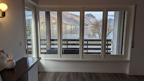 Una habitación con un amplio ventanal con vistas a un lago y montañas.
