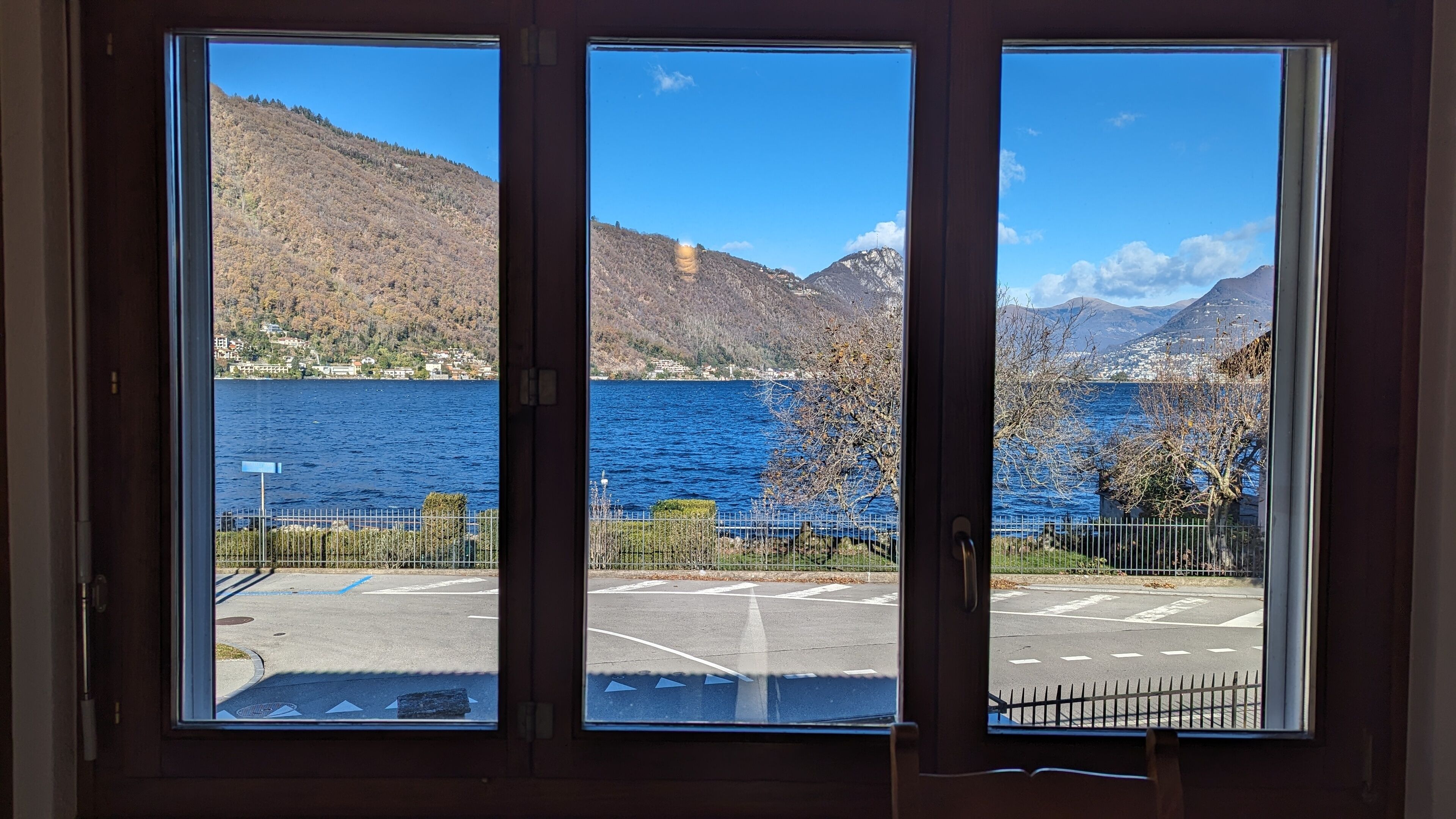 Une vue à travers une fenêtre donnant sur un parking et un lac.