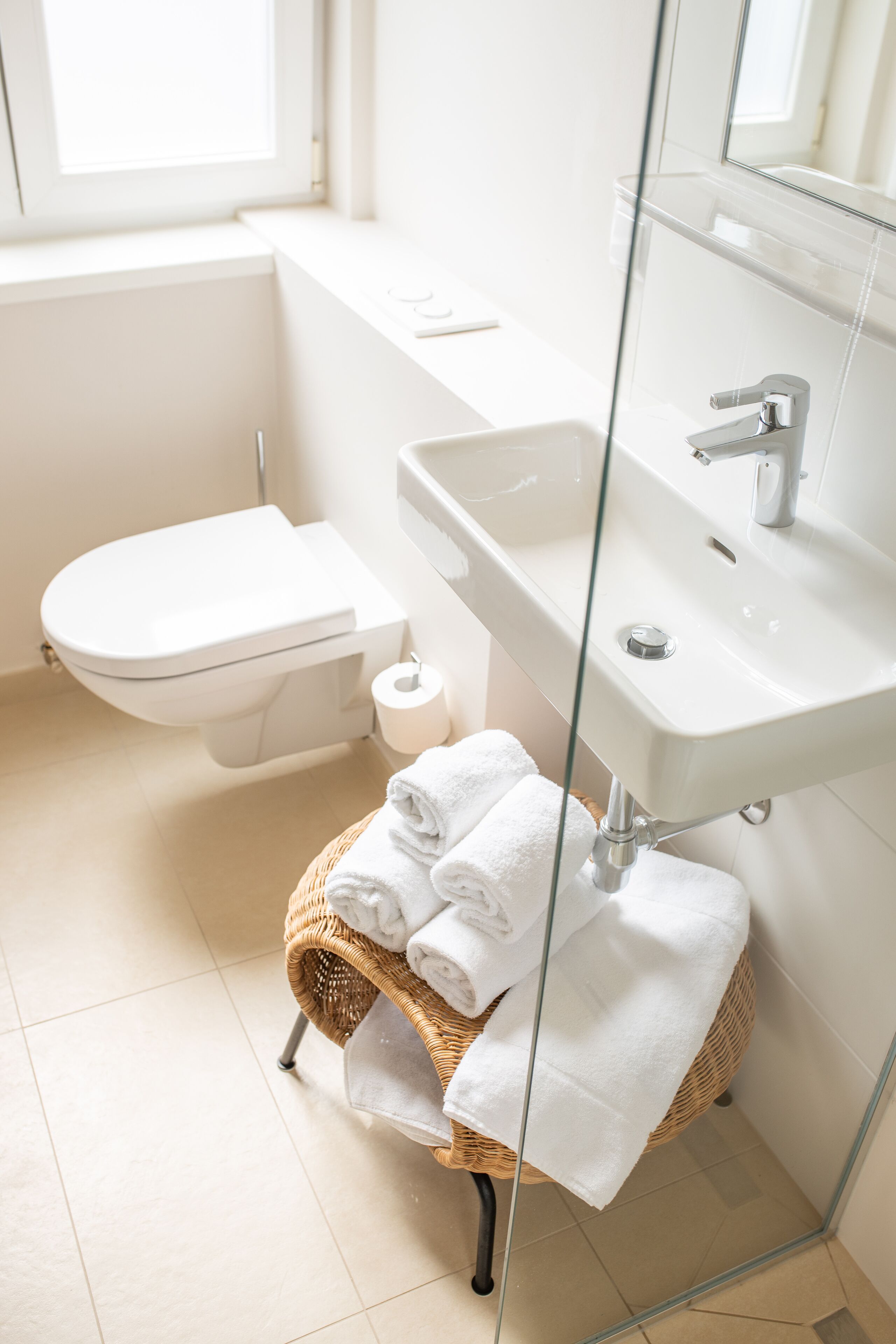 Ein modernes Badezimmer mit Toilette, Waschbecken und einem Korbwäscheschrank mit Handtüchern.
