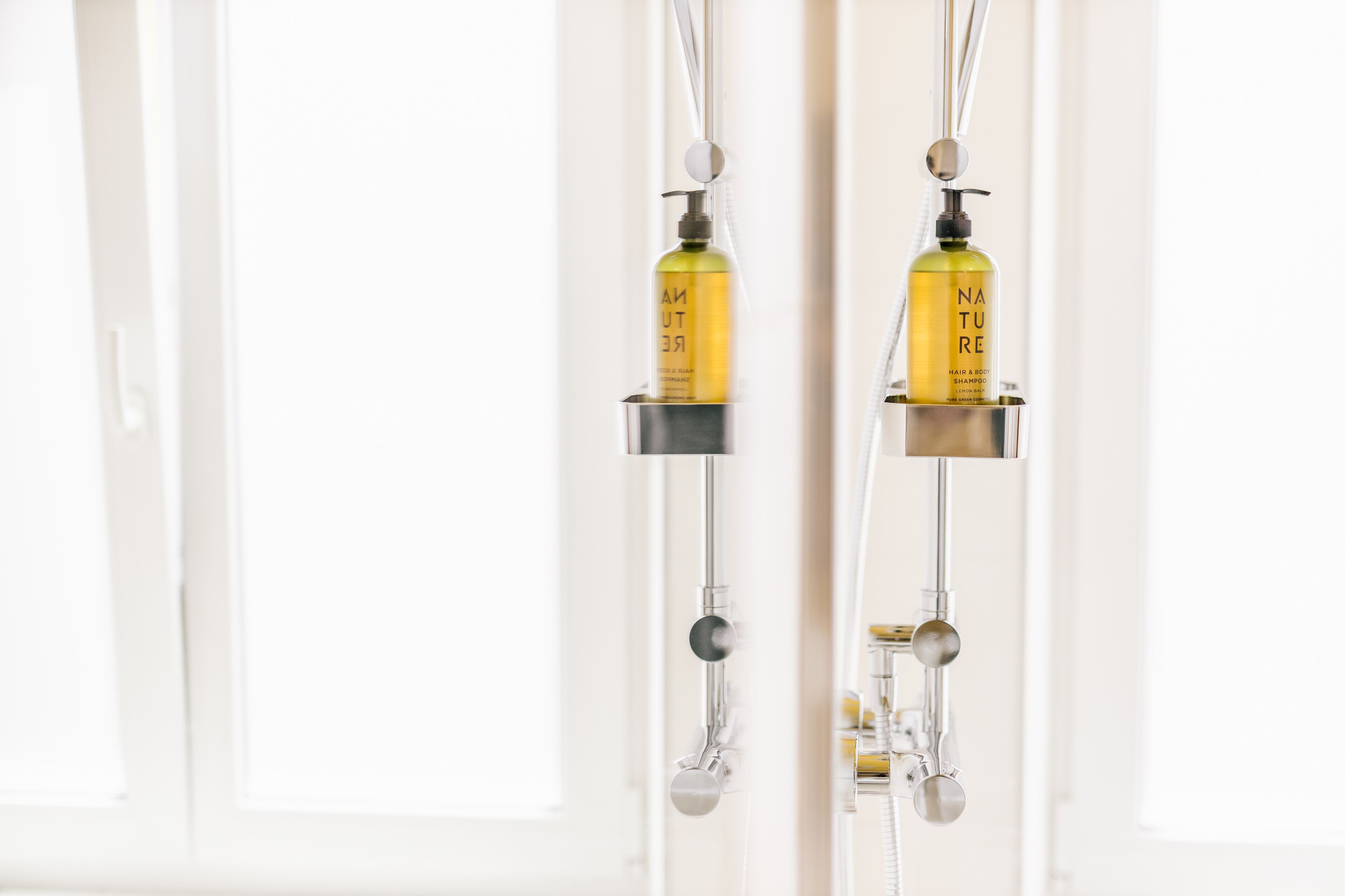 Une salle de bain équipée d’une douche et comprenant deux bouteilles de shampoing.