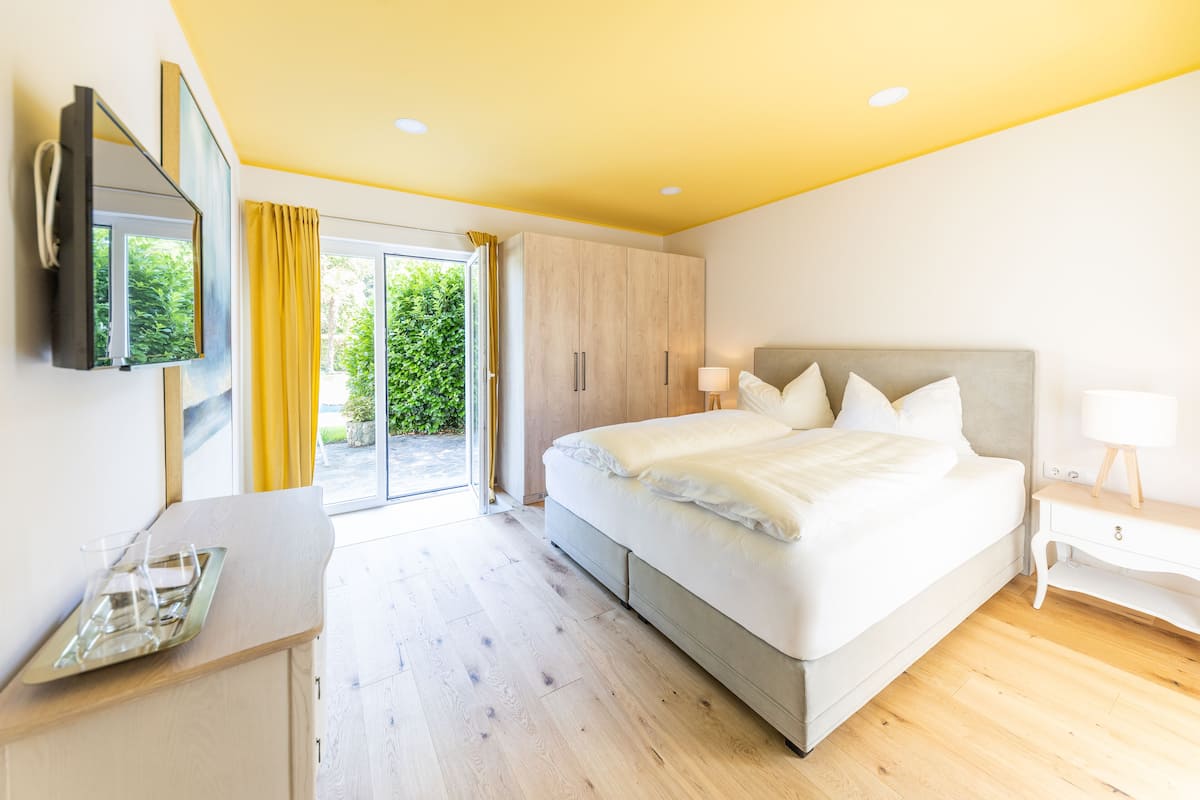Une chambre moderne avec un grand lit, un bureau et un téléviseur fixé au mur.