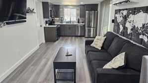 A modern kitchen with stainless steel appliances, a grey sofa with decorative pillows, and a world map on the wall. - Spectacular Modern Luxury! (Tillamook)
