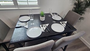 A dining table set with plates, cutlery, and glasses, surrounded by grey upholstered chairs. - Spectacular Modern Luxury! (Tillamook)