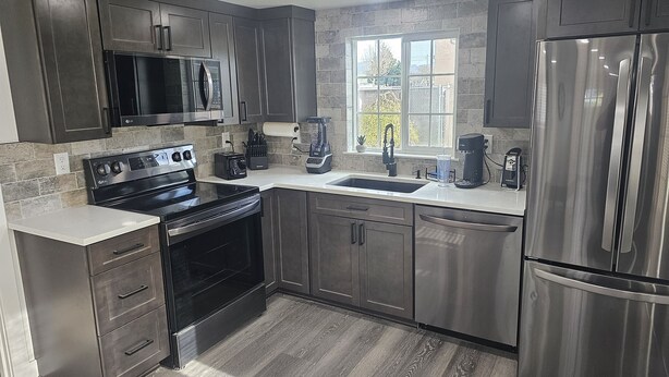 A modern kitchen with stainless steel appliances, a large window, and a stone backsplash. - Spectacular Modern Luxury! (Tillamook)