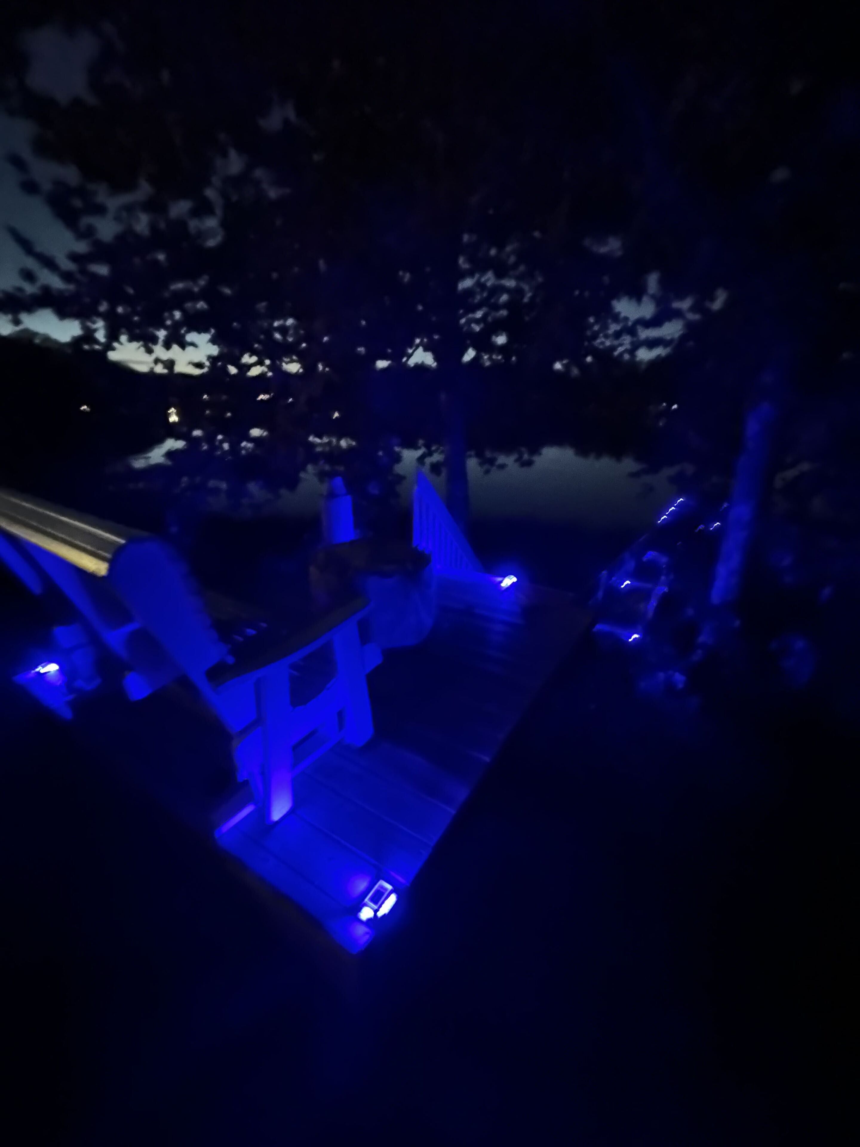 A dimly lit outdoor area with a wooden deck and blue ambient lighting.