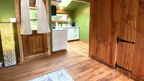 A rustic kitchen with wooden beams, a white countertop, and a large wooden door. - Private garden cottage located in the heart of downtown.  (Leesburg)