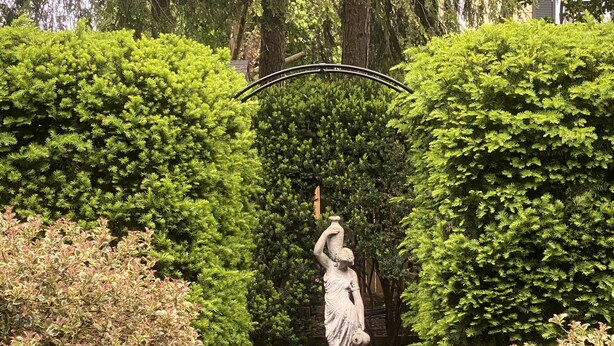 A statue in a garden with a brick pathway. - Private garden cottage located in the heart of downtown.  (Leesburg)