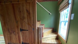 A room with wooden flooring, a large wooden door, a staircase, and a window with blinds. - Private garden cottage located in the heart of downtown.  (Leesburg)