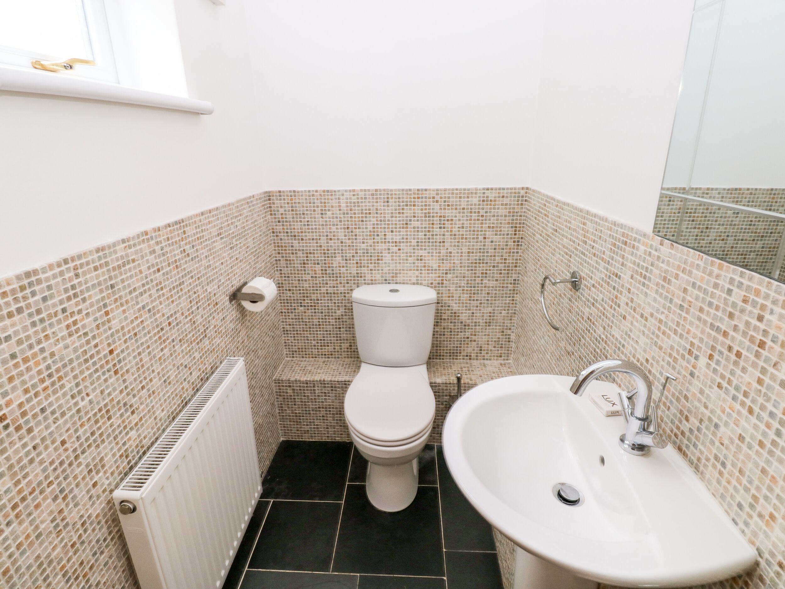 Un bagno piccolo con il water, un lavandino e pareti rivestite di piastrelle.