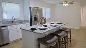 A modern kitchen with white cabinets, a granite countertop, a built-in refrigerator, and a ceiling fan. - 3 bed 2 bath with lovely outdoor space (Lebanon)
