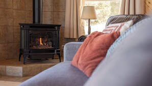 A cozy living room with a fireplace, a sofa, and a lamp. - Dunes Rest (Mosca)