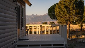 A wooden cabin with a porch, a stone pathway, and a view of mountains. - Dunes Rest (Mosca)