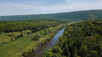 A river flowing through a densely forested valley with rolling hills in the background.
