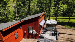 A red cabin with a small porch and a covered outdoor seating area.