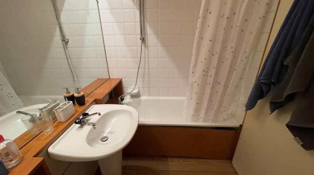 A bathroom with a white sink, wooden vanity, and a shower with a curtain.