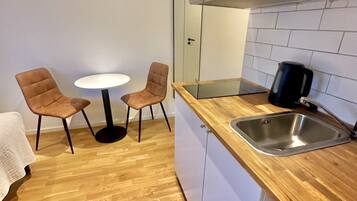 Una cocina compacta con encimera de madera, un lavamanos de acero inoxidable y dos sillas alrededor de una pequeña mesa.