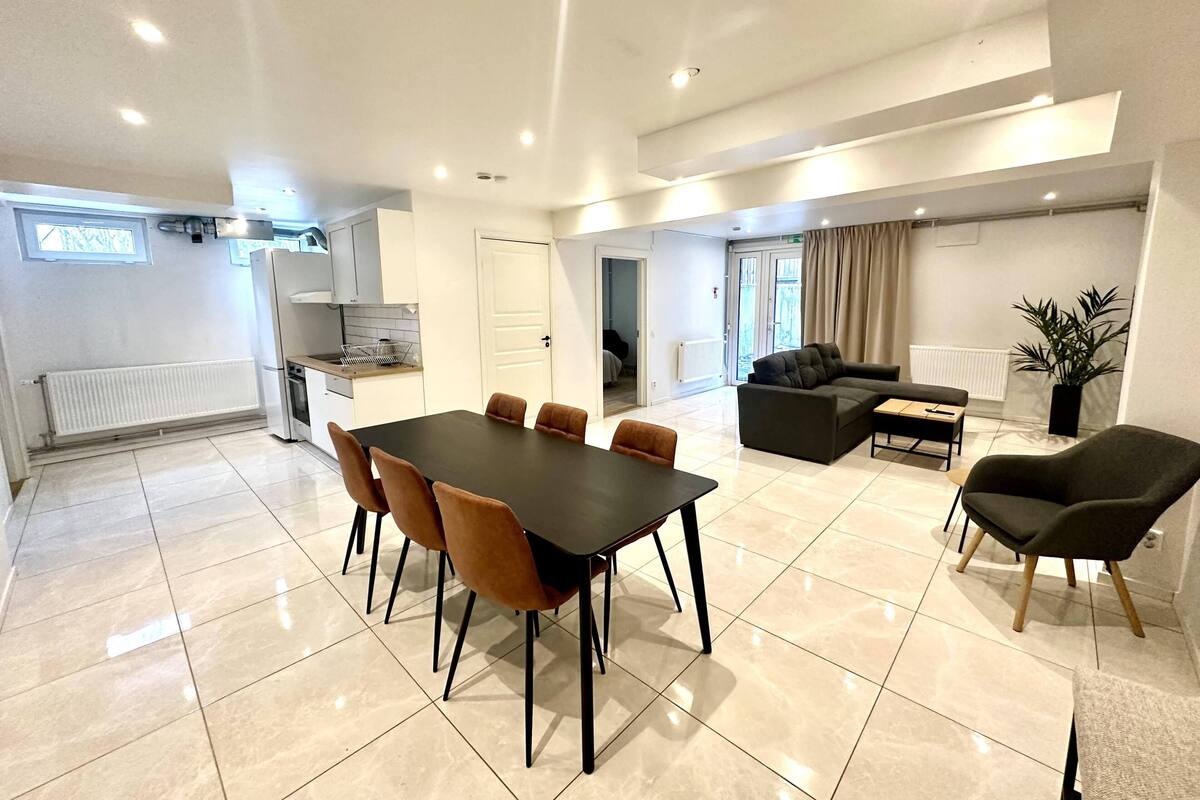 Een moderne woonkamer met een eettafel, banken en een keukenhoek.