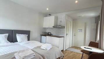 Una habitación de hotel moderna con dos camas, kitchenette, comedor y baño.