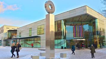 Un edificio moderno con facciata in vetro e una scultura circolare di rilievo di fronte.