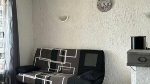 Et værelse med sofa, vækkeur, væglampe og skab.