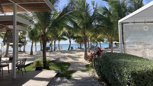 A beachside patio with a wooden deck, lounge chairs, and a view of the ocean.